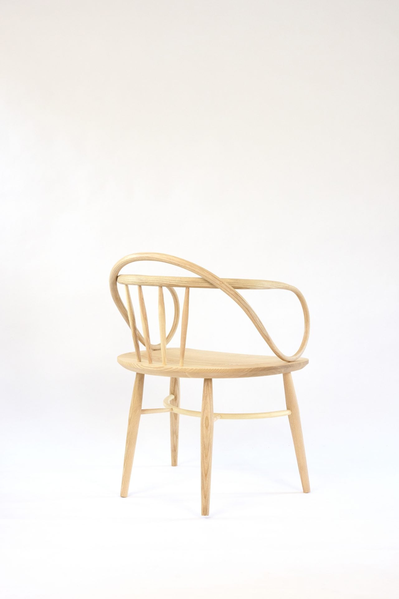 A light wood Windsor chair with a curved back and armrests.