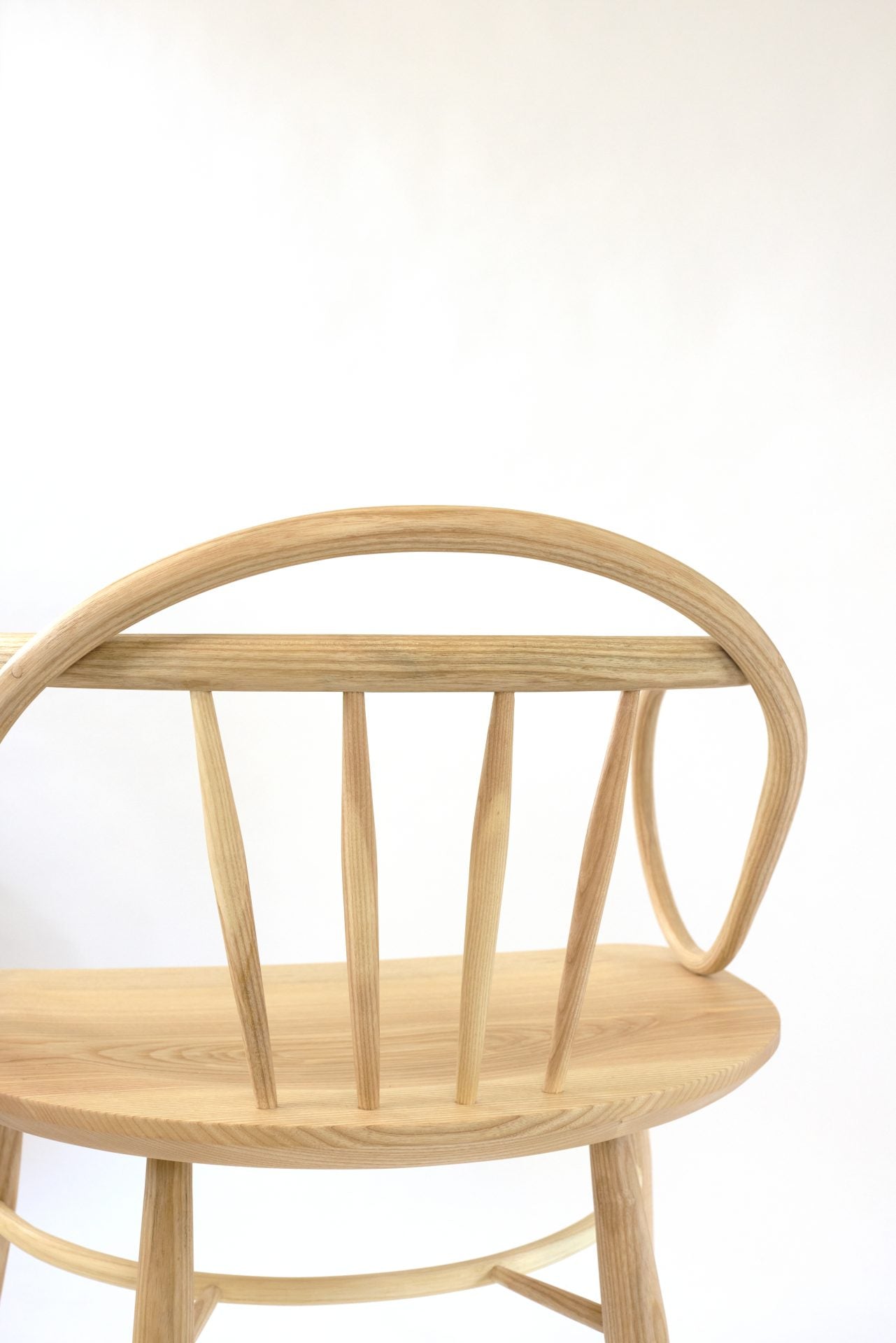 Solid ash and teak Windsor chair with a curved back and spindle supports.
