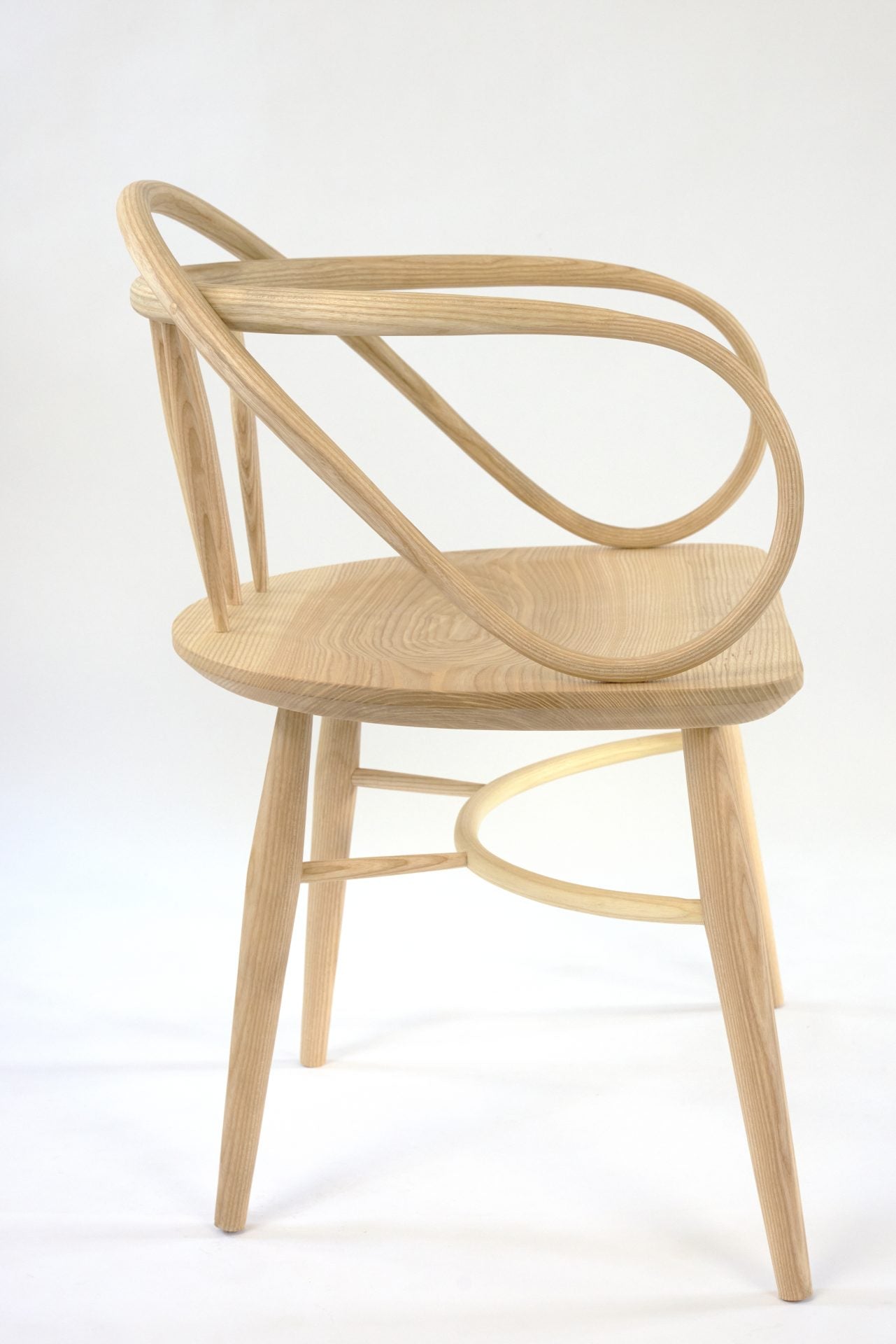 A light wood Windsor chair with a double bow back and curved arms.