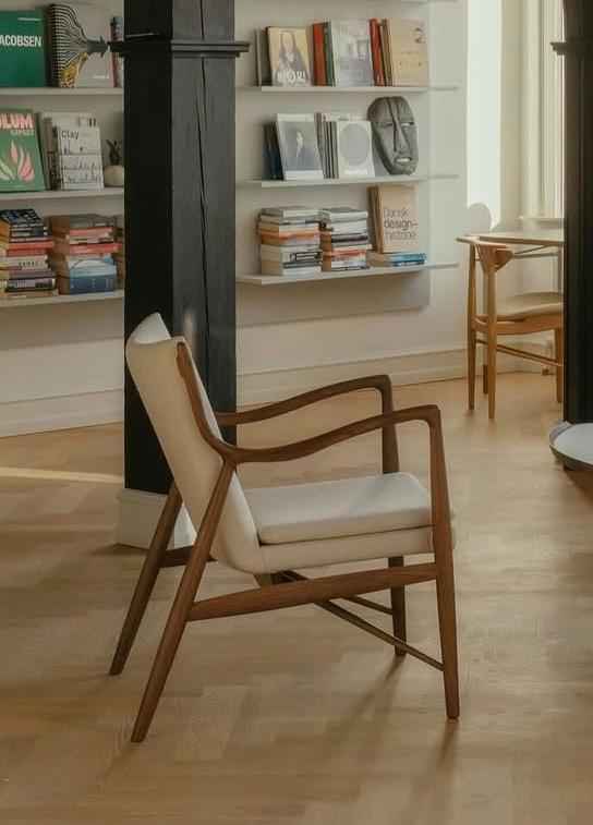 A Finn Juhl 45 Chair with a teak wood frame and light-colored upholstered seat and backrest.