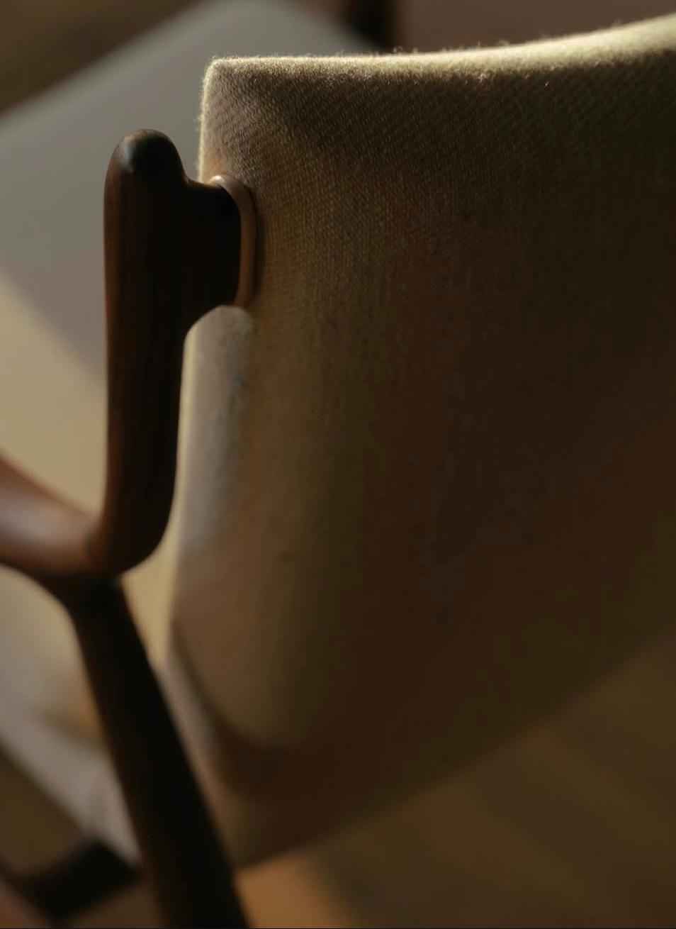 A close-up view of the teak wood frame and upholstered backrest of a Finn Juhl 45 Chair.