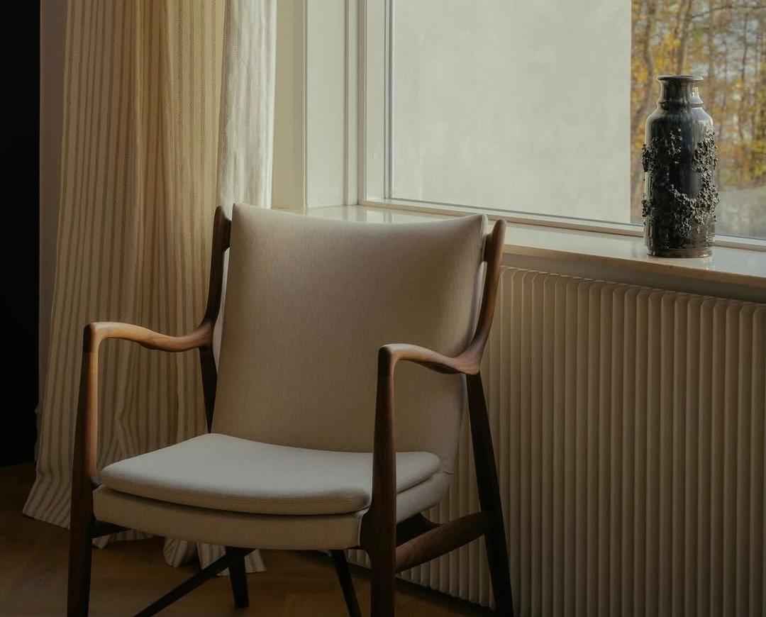 Finn Juhl 45 Chair with a dark wood frame and light-colored upholstered seat and backrest.