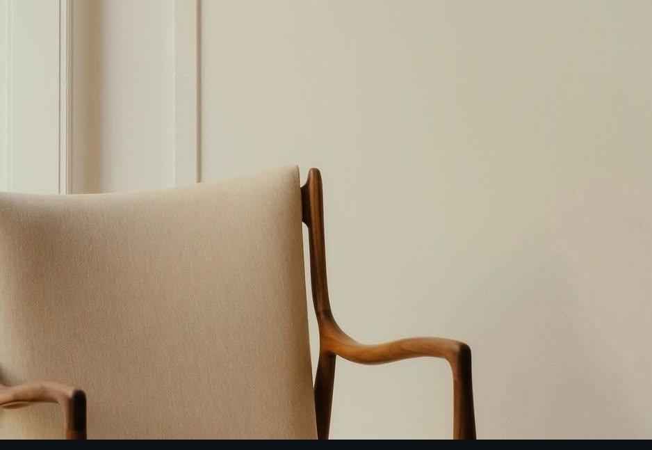 A Finn Juhl 45 chair with a teak wood frame and light beige upholstered seat and backrest.