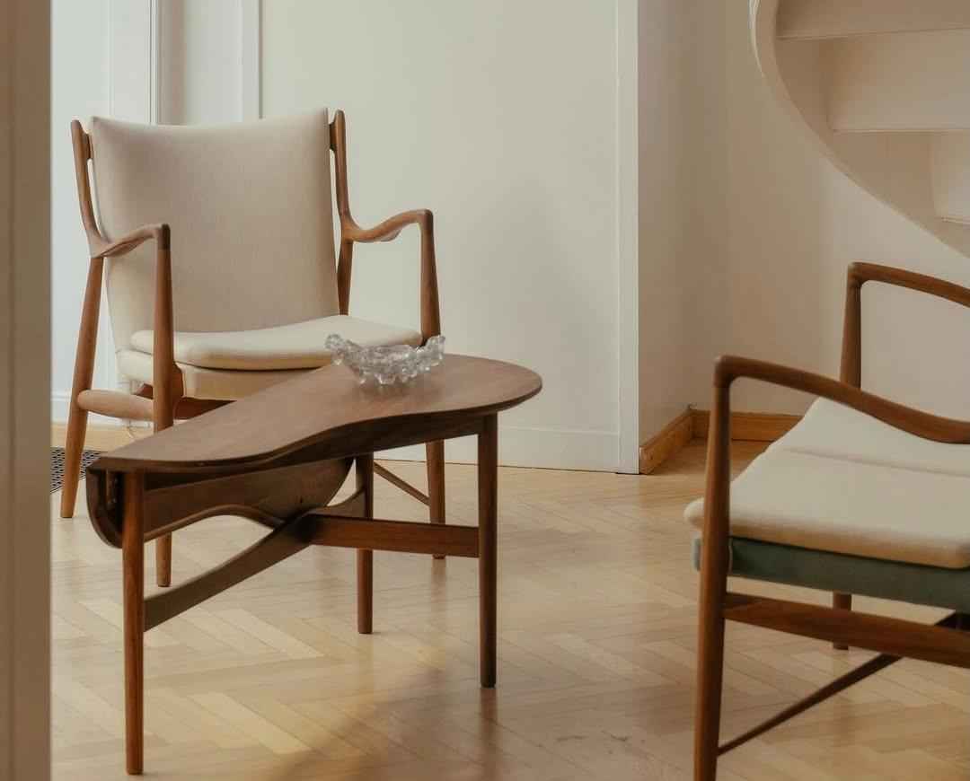 A Finn Juhl 45 Chair with a teak frame and light-colored upholstery in a minimalist room.