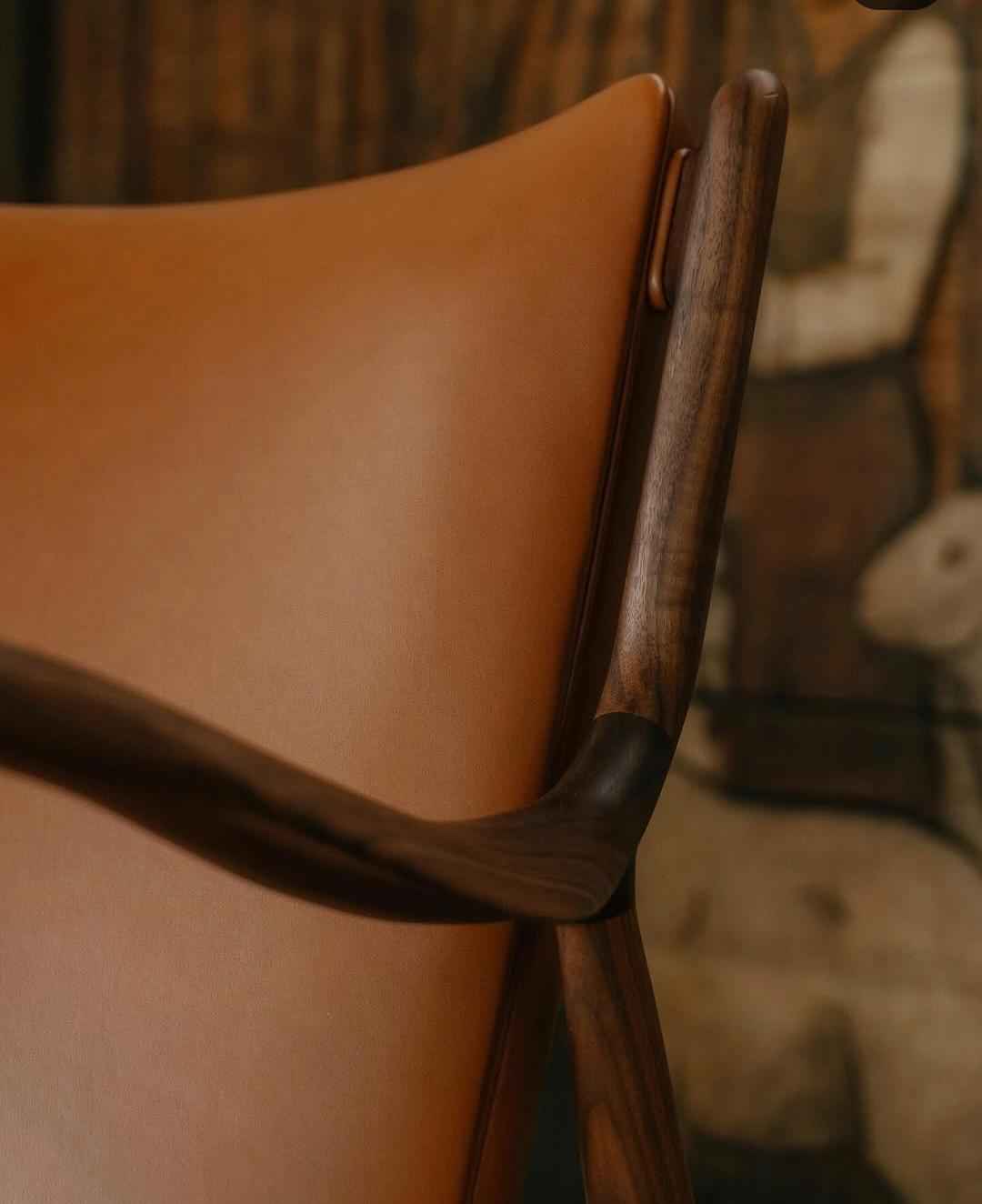 A close-up view of the Finn Juhl 45 Chair featuring a dark wood frame and tan leather upholstery.
