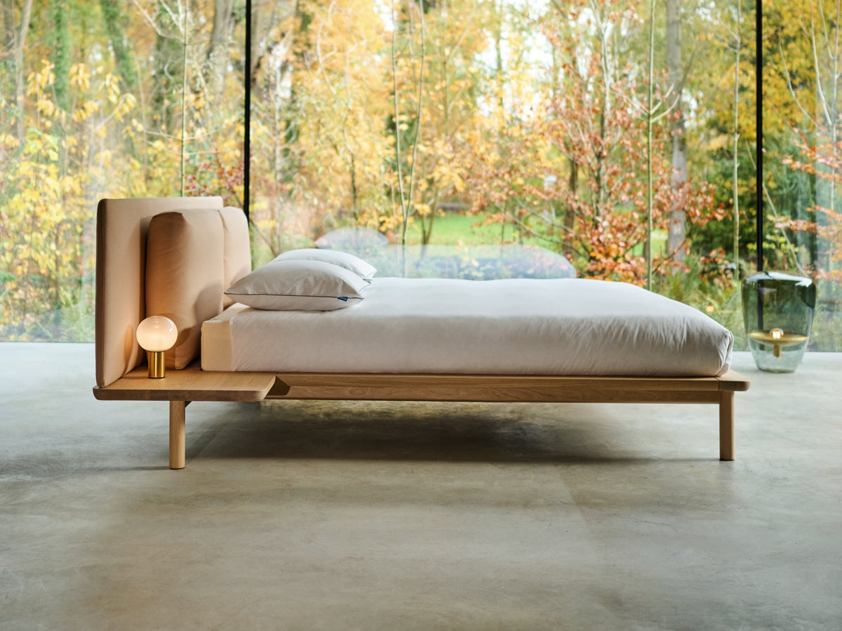 Noble style bed with a broad frame and upholstered headboard; design reference for Gulmohar Wood Works, Bangalore