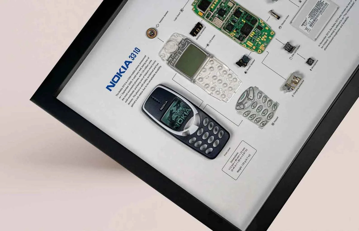 A framed display featuring a disassembled Nokia 3310 with its components labeled on a white background.